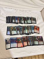 Stacked view of approximately 100 foil Magic: The Gathering cards spread on cloth background