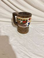 Front view of carved wooden mug with painted folk motifs
