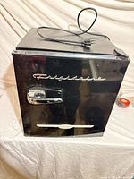 Front view showing Frigidaire logo, chrome handle, black gloss finish