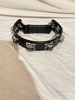 Front view of black half-moon tambourine showing jingles and handle