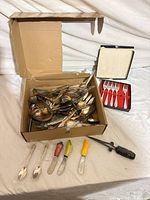 Overall lot showing loose flatware, boxed forks, spreaders, pick tool and wrapped spoons