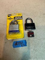 Tradesman laminated padlock in package and Master black padlock with key block on surface