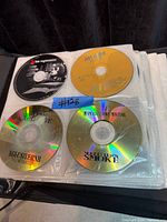 Four CDs in binder sleeves including Kanye West, John Legend, mix CDs