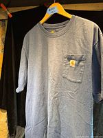 Full view of Carhartt heather blue pocket T-shirt hanging