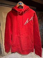 Front view of red Fila Lazarus hoodie showing kangaroo pocket and white script logo