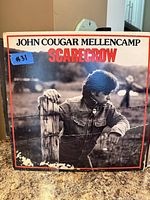 Front cover of John Cougar Mellencamp Scarecrow LP showing artwork and wear