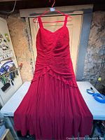 Front view of red evening dress hanging, showing full length and skirt