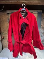 Front view of red double-breasted winter coat with belt displayed on hanger