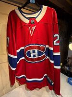 Front view of red Montreal Canadiens jersey showing crest, number 20 on sleeve, lace-up collar