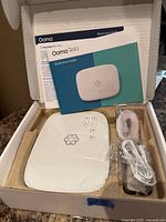 Box opened showing Ooma Telo device, power adapter, cable and documentation
