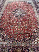 Full length view of Persian Kashan rug showing red field, blue medallion and borders