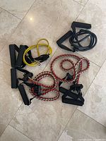 All four resistance bands arranged on tile floor showing colors and handles