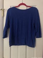 Full back view of blue ribbed 3/4-sleeve sweater on hanger