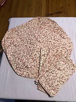 Stacked view showing four oval placemats and folded napkins with pink and cream floral print