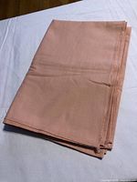 Folded pink rectangular tablecloth showing hem and texture