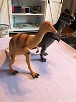 Both plastic dinosaur figures standing on table