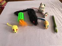 All six cat toys laid out with pen for scale