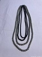 Full view showing four strands of black and silver-tone round beads