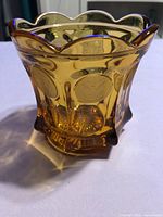 Full view of amber glass jar showing scalloped rim and coin pattern
