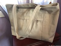 Oblique view showing exterior front with zipper pocket, slip pocket, straps