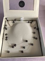 Necklace in presentation box showing pearls on clear filament