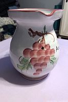 Front view of hand-painted stoneware wine jug showing grape motif