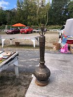 Full view of ornate metal lamp on wood base with harp, no shade