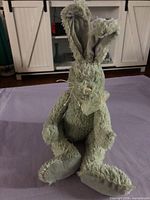 Front view of light green plush bunny seated on surface