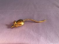 Front view of gold plated mouse brooch showing CZ tail and green eyes