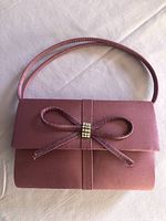 Full view of orchid satin clutch with bow and strap