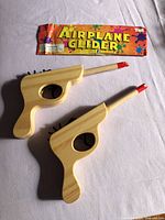 Overall view of two wooden rubber band guns and Airplane Glider package