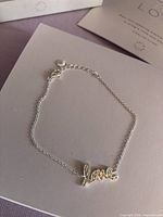 Bracelet laid flat showing chain, love charm, clasp and extender