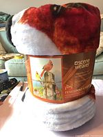 Rolled blanket with front of label showing Scene Weaver branding and cardinal graphic
