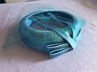Top angle of blue satin pillbox hat showing veil and bow