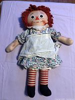 Full view of Raggedy Ann doll on fabric surface