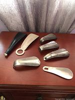 All seven shoe horns laid out showing design and materials