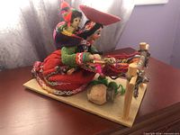 Front left view showing woman at loom, child on back, clay pot and wooden base