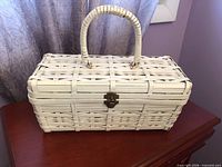 Front view showing white wicker basket with handle and latch
