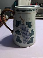 Full view of stoneware pitcher showing grapevine decoration and handle