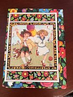 Front of floral folio with one card showing illustration of two children running with balloons