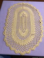 Full view of oval yellow crochet doily on surface