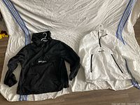 Black and white windbreakers side by side on sheet