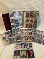 Binder open showing pages of basketball cards and additional sleeved cards laid out