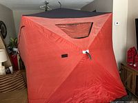 Exterior view of red pop-up ice fishing hut showing window and roof
