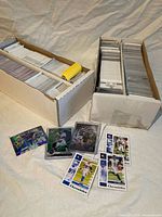 Two storage boxes loaded with trading cards, several sleeved cards laid out in front