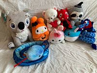 Group shot of all nine plush toys lined up on white cloth