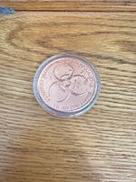 Full view of copper round in capsule on wood surface