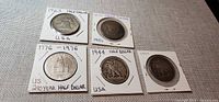 Five half dollars in holders showing dates 1963, 1951, 1776-1976, 1944 and 1941