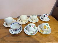 Seven assorted teacup and saucer sets displayed