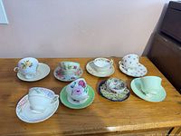 All eight teacup and saucer sets laid out on table